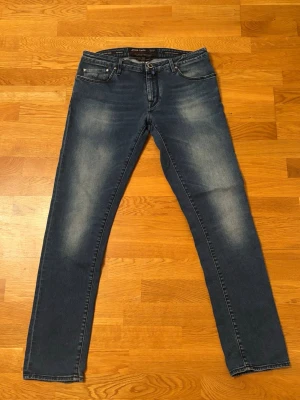 Slim jeans från Jacob Cohen - Snygga blå slim fit jeans från Jacob Cohen med klassisk modell som är slim. Jeansen har en broderad detalj på myntfickan och är tillverkade i mjuk denim med stretch för extra komfort. Storlekslappen är avklippt på grund av oskönhet. Storlek 33 men skulle säga att den passar 32 