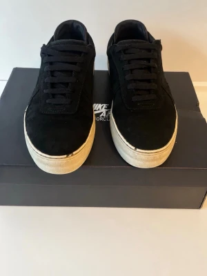 Svarta Nike sneakers i mocka - Hej, säljer dessa snygga Axel Arigato skor som är i storlek 41.  Skorna är använda. Lite sönder framför som ni kan se och under skorna men inget man märker när man har på sig de. Bara skor ingår !