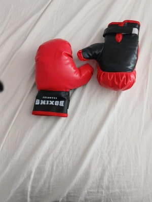 Röda och svarta leksaks/barn boxningshandskar - Bokningshandskar. Funkar för mindre barn och är inte riktiga boxningshandskar. Kan ej träna riktigt med dem. 