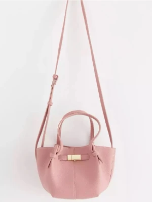 Lindex Rosa axelväska med gulddetalj - Söt rosa axelväska i mjukt konstläder med justerbar axelrem och två handtag. Väskan har en snygg guldfärgad detalj framtill och en stilren, lätt fyrkantig form. Perfekt för dig som vill ha en trendig och praktisk väska med plats för det viktigaste.