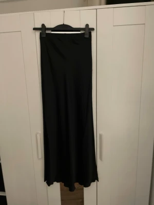 Svart maxi kjol i satin - Svart maxi kjol i satin från Lindex i storlek xs. Använd 1 gång. Köpt för 500kr säljer för 400kr