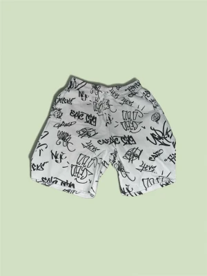 Vita shorts med graffiti-tryck - Säljer ett par vita shorts med svart graffiti-inspirerat tryck över hela plagget. Shortsen har elastisk midja med snörning och avslappnad passform. Perfekta för dig som gillar streetwear och vill sticka ut lite extra. Storlek: 158 EUR. Skriv privat för fler bilder