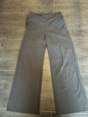 Vida grå byxor med stretch från Aimn - Grå byxor med vida ben, fickor fram och hög midja. Byxorna är tillverkade i ett stretchigt material som ger en skön och flexibel passform. ” Petite pants”, betyder att byxorna är i lite kortare modell så det passar de som är lite kortare. 