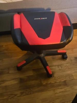 DXRacer. FOTPALL - Säljer en svart och röd sits från DXRacer, ursprungligen från en gamingstol. Sitsen har sportig design med röda detaljer och DXRacer-logga framtill. Materialet är konstläder och sitsen har hjul och armstöd.