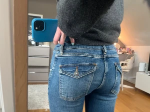 Blå slim fit jeans med fickdetaljer - Snygga blå slim fit jeans med klassiska bakfickor och coola sömdetaljer. Jeansen har en mellanblå tvätt och smal passform som sitter tajt. Perfekta för en trendig och avslappnad look. (Är 170cm står ingen storlek men ungefär xs-s)