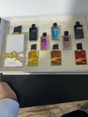 YSL parfym  - Exklusivt parfymset från Yves Saint Laurent med  8 olika miniflaskor och en stor 100 m i olika färger och former. Flaskorna har eleganta detaljer i guld och svart, och levereras i en lyxig vit och guldig presentask med YSL-logga. Perfekt för dig som vill testa flera dofter från YSL. Och till dig som vill köpa present till någon så kan du köpa sån.
