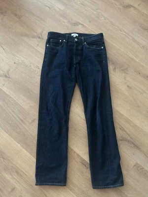 Mörkblå raka jeans - Snygga mörkblå jeans med rak passform och klassisk femficksdesign. Jeansen har silverfärgade nitar och kontrastsömmar. Perfekta för en stilren och enkel look.