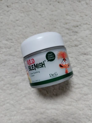Dr.G Red Blemish Soothing Cream - En ansiktskräm från Dr.G, Red Blemish Clear Soothing Cream, i en vit och grön burk med tecknade figurer på etiketten. Krämen är framtagen för att lugna och återfukta huden och passar särskilt för känslig eller irriterad hud.