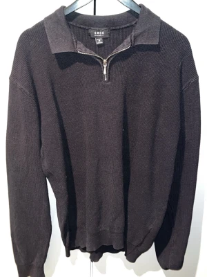 Svart stickad tröja med half zip SMOG - Svart stickad tröja från SMOG i regular fit med halv dragkedja vid kragen. Tröjan har lång ärm och klassisk design som passar perfekt till jeans eller chinos. Enkel och stilren look för dig som gillar basic men snyggt. Storlek M.