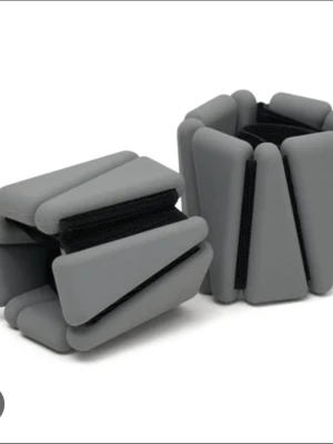Grå träningsvikter för handleder - Säljer ett par grå träningsvikter för handleder eller vrister. De har en modern design med justerbar kardborre och är tillverkade i mjukt silikonmaterial. Perfekta för att addera extra motstånd vid träning, yoga eller promenader.