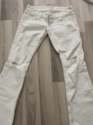 Vita lågmidjade jeans från Gina 14+ - Säljer ett par vita jeans med slitningar på låren och snyggt broderade bakfickor. Jeansen har låg midja och raka ben. Perfekta för dig som gillar en avslappnad och trendig stil. Materialet är bomull med lite stretch för extra komfort. Använda 1-2 gånger💗