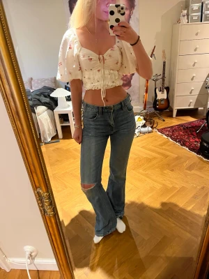 Blå bootcut jeans med slitning Levis - Säljer ett par blå bootcut jeans med en snygg slitning vid knät. Jeansen har klassisk femficksdesign och medelhög midja. Perfekta för dig som gillar en avslappnad och trendig stil. Materialet är denim i bomull. Från Levis! Långa på mig som är 170. Mått på bilderna