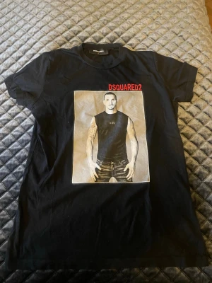 Svart DSQUARED2 t-shirt med tryck - Cool svart t-shirt från DSQUARED2 med stort grafiskt tryck av Zlatan på framsidan och röd DSQUARED2-logga upptill. Klassisk rund hals och korta ärmar. Perfekt för dig som gillar streetwear och vill sticka ut. Finns inte nånstans att köpa
