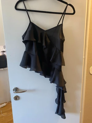 Svart volangtop från Gina Tricot - Snygg svart topp från Gina Tricot med volanger, använts vid 1 tillfälle!!
