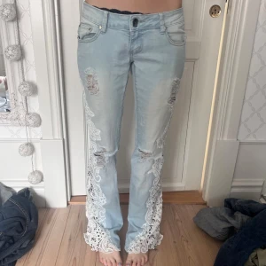 Superlågmidjade bootcut ljusblåa jeans med spets - Sååå snygga! Midja ca 38 innerben ca 81! Se sista bilder för defekter