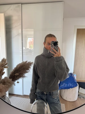 Grå stickad kofta - Mysig grå stickad kofta med oversized passform och långa ärmar. Tröjan har en hög, bred polokrage och är ribbstickad för extra struktur. Perfekt att styla med jeans för en avslappnad look. Köpt på NA-KD i storlek XS