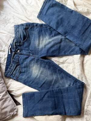 Blå slim fit jeans från Strömberg - Snygga blå slim fit jeans från Strömberg med klassisk femficksdesign och slitna detaljer på låren. Jeansen har normal midja och är tillverkade i ett mjukt denimtyg som ger en skön passform. Perfekta för en avslappnad och trendig look. Nästan aldrig använt dem 