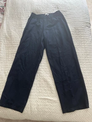 Mörkblå linnebyxor  - Säljer ett par mörkblå linnebyxor med avslappnad passform och resår i midjan. Byxorna har raka ben och sidofickor, perfekta för en chill och stilren look. Materialet är lätt och luftigt linne, vilket gör dem sköna att bära under varma dagar.