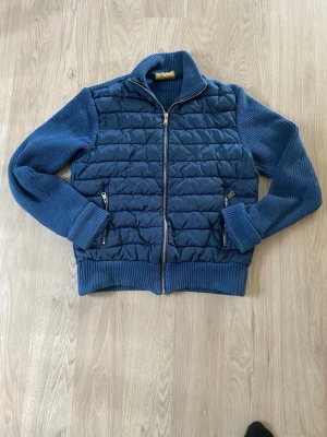 Vonroe cardigan - Mörkblå cardiganjacka med quiltad framsida och stickade ärmar samt rygg. Jackan har dragkedja framtill, två fickor med dragkedja och ribbade muddar. Perfekt för lager-på-lager och snygg till jeans.