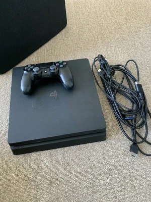 PlayStation 4 Slim med handkontroll - Svart PlayStation 4 Slim från Sony med stilren, fyrkantig design i matt plast. Konsolen kommer med en svart DualShock 4-handkontroll och tillhörande kablar för anslutning. Perfekt för dig som vill spela de senaste spelen eller streama film. Säljer detta då jag inte längre spelar på det 