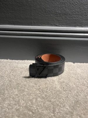 Bälte - Snyggt svart bälte från zara med klassiskt rutigt mönster och mattsvart spänne. Bältet har en lyxig känsla med insida i brunt skinn och passar perfekt till jeans eller kostymbyxor.