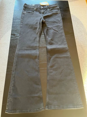 Svarta nya flare lowwaist jeans från HM - Snygga svarta flare low waist från HM divided. Jeansen har utsvängda ben (flare) och är tillverkade i stretchigt denimtyg.  Nya med tagg, aldrig använda. Jeansen ser aningen grå ut på bilderna men jeansen är mer svarta. 
