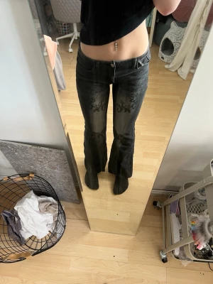 Svarta bootcut jeans med tryck - Säljer ett par svarta bootcut jeans med snygga mönster på både fram och baksida. Jeansen har låg midja och klassisk femficksdesign. Materialet är denim med stretch för bra passform. Perfekt för alla stilar! Dem sitter perfekt på dig som är runt 160 lång och har storlek S-M. Dom har stygn precis nedanför gylfen som ni ser på sista bilden. Detta då jag tänkte sy om dom, men ångrade mig efter att jag klippt upp där. Men detta är som ni ser inget som syns när dom sitter på. Det är säkert ihop sytt! 