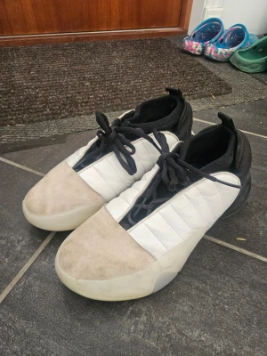 Adidas harden volume 7 Basket skor vit/svart - Säljer ett par Adidas Harden volume 7 basketskor med svart och vit ovandel, beige mocka på tån och svarta detaljer. Skorna har snörning, quiltade paneler på sidorna och klassiska svarta ränder på hälen. Säljer då jag slutat med basket men dem är perfekta för att spela basket och har bra support för vristen och det finns även en insula i för dem med hälproblem eller som bara vill ha en skönare sula, går att ta bort enkelt. Dem har bra studs och att hoppa o springa känns otroligt enkelt.