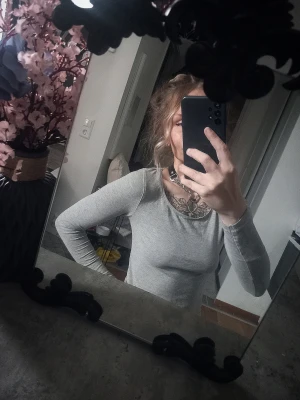 Ljusgrå långärmad topp - En enkel och stilren ljusgrå långärmad topp med rund halsringning. Toppen har en tight passform och är perfekt att matcha med olika outfits. Passar dig som gillar minimalistisk stil.