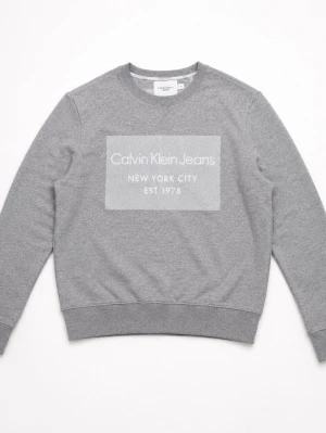 Grå sweatshirt från Calvin Klein Jeans - Snygg grå sweatshirt från Calvin Klein Jeans med stort vitt tryck på bröstet där det står 'Calvin Klein Jeans New York City EST 1978'. Tröjan har rund halsringning, ribbade muddar och är tillverkad i mjuk bomullsblandning.