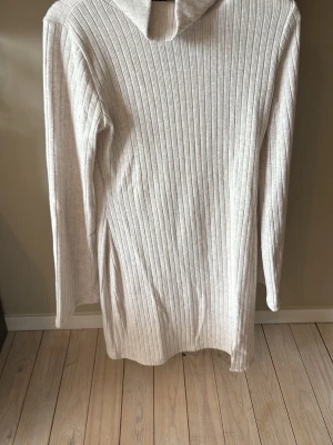 Ljusbeige ribbad polotröja Gina Tricot - Säljer en ljusbeige, långärmad stickad polotröja från Gina Tricot. Tröjan har ribbad struktur och en hög polokrage som ger en snygg och avslappnad look. Perfekt att styla med jeans eller kjol för en trendig outfit.