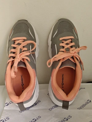 Grå och persikofärgade sneakers 41 - Chunky sneakers från Stormberg i grått, vitt och persikofärg. Ovandel i mesh och syntet med vita och svarta detaljer på sulan. Sköna och trendiga med lågt skaft och färgglada snören. Perfekta för dig som gillar sportig stil.