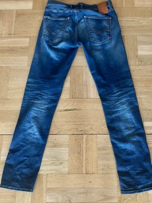 Blå slim fit jeans från Nudie Jeans - Säljer ett par blå slim fit jeans från Nudie Jeans med klassisk femficksmodell och snygga slitningar. Jeansen är knappt använda och har en skön fade.