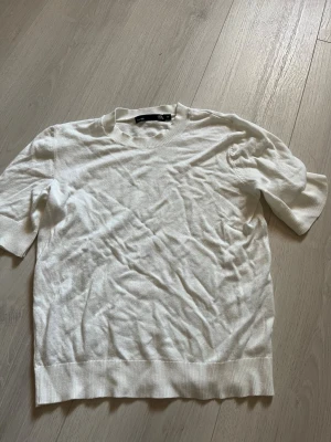 Vit kortärmad topp från H&M - En enkel och stilren vit topp  med rund halsringning och korta ärmar. Tillverkad i mjuk bomull för en bekväm känsla. Perfekt att matcha med jeans eller kjol för en clean look.