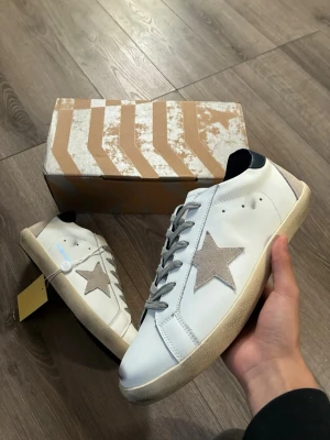 Vita Golden Goose sneakers med stjärna - Snygga vita sneakers från Golden Goose med grå stjärna på sidan och grå skosnören🤗 storlek 43 och inga fel, hör av er vid funderingar 