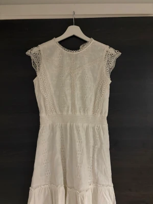 Vit klänning från THE NEW - Vit klänning från THE NEW med broderade detaljer och spets vid ärmar och hals. Endast använd en gång, men är som nyskick. 💕