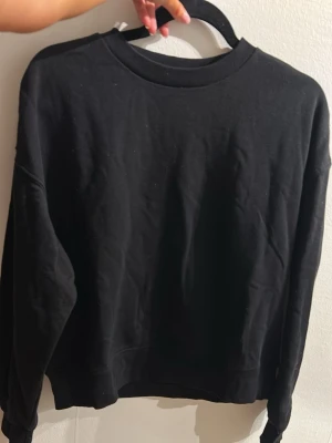 Svart sweatshirt från H&M  - En enkel och stilren svart sweatshirt från H&M Divided. Tröjan har rund halsringning, långa ärmar och ribbade muddar vid ärmslut och nederkant. Perfekt basplagg i mjukt material som passar till allt. Super skön🥰Inte så varm, lite ”tunnare” i materialet