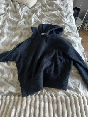 Marinblå hoodie från Gina Tricot - Mysig stickad hoodie från Gina Tricot i storlek 158/164. Tröjan har en klassisk huva och är tillverkad i ett mjukt, stickat material som känns skönt mot huden. Perfekt för dig som gillar en enkel och stilren look med en avslappnad vibe.