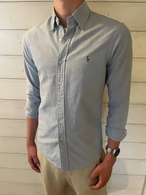 Ralph Lauren skjorta  - En snygg ljusblå skjorta från Ralph Lauren.            Slim fit                                                               Skjortan är i nytt skick i storlek S.                    Skriv gärna vid några frågor!