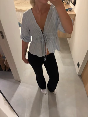 Blåvit randig blus med knytning - Snygg blåvit randig blus med djup v-ringning och knytband i midjan. Blusen har trekvartsärm och ett lätt, luftigt tyg🌸