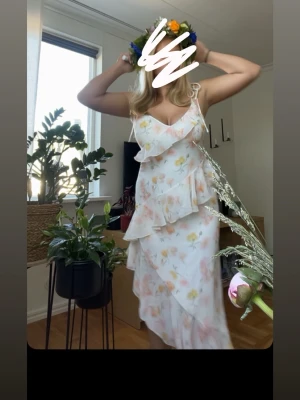 Blommig volangklänning Gina Tricot - Säljer en långklänning från Gina Tricot med blommigt mönster. Klänningen har volangdetaljer, v-ringning och smala axelband som man knyter. Perfekt för sommarens alla tillfällen och midsommarfirande.
