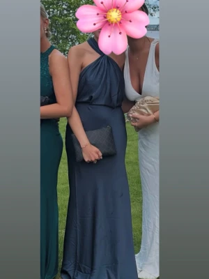 Mörkblå balklänning  - Snygg mörkblå långklänning med halterneck och draperad överdel. Klänningen har en elegant, figurnära passform och är ärmlös. Perfekt för student eller bal. Materialet har en lätt glansig finish. Jag är 170, köpt begagnad men bra skick