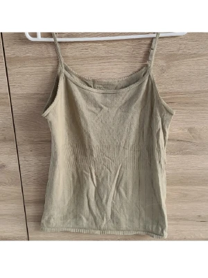 Grönt pointelle linne - Olivgrönt/khaki linne med pointelle mönster. Toppen har smala justerbara axelband och söta detaljer i tyget. Har även ett i vit. Från Noa Noa i stolek L i 100% bomull i bra skick.