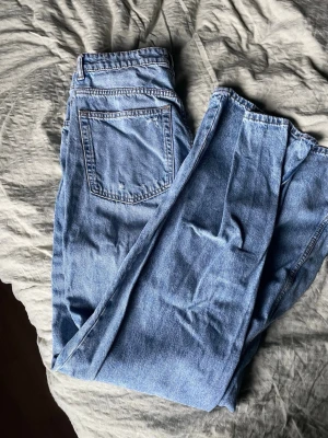 Blå vida jeans  - Vida jeans med slitningar. Hög midja. 