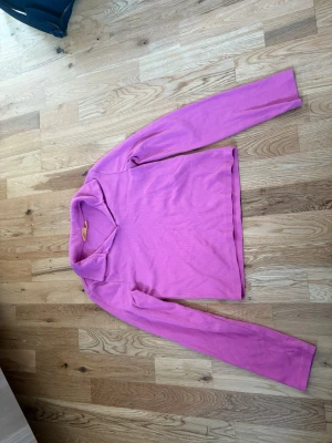 Rosa  långärmad tröja med krage - En stilren ljuslila långärmad tröja med mjuk krage. Tröjan har en rak passform och är tillverkad i ett tunt, stretchigt material som känns skönt mot huden. Perfekt för dig som gillar färg och vill ha en enkel men snygg look.