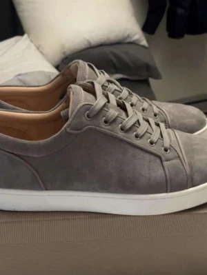 Söker gråa lubs - Snygga grå sneakers i mocka med klassisk låg profil och vita sulor. Skorna har matchande grå skosnören och diskreta sömmar för en clean look. Perfekta för dig som gillar stilrena och minimalistiska sneakers.