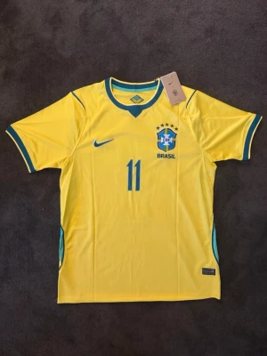 Brasilien VM 26/27 hemma Raphinha 11 - Fotbollströja med Raphinha på ryggen. Tröjan är helt ny med tagg kvar och i perfekt skick. Storlek M. Perfekt för dig som är supporter, samlar på fotbollströjor eller vill ha en snygg tröja till träning och vardag. 