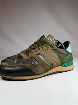 Valentino Rockrunners - Snygga sneakers från Valentino med camomönster i grönt, brunt och svart. Skorna har detaljer i mocka, läder och textil samt en unik grön häl med nitar och ljusblå bakdel. Klassisk låg modell med snörning och bekväm sula. Storlek 42 men passar 43