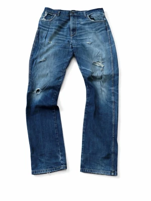 Vintage Wrangler jeans - Blåa distressed Wrangler jeans. W36 L34. Bra skick med coola detaljer. Modell på byxorna är texas. W36 är generellt stort men om man har bälte så passar de bra