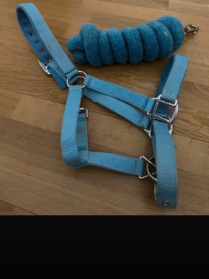 Blå grimma och rep till häst - Säljer en ljusblå grimma i slitstark nylon med matchande blått grimskaft. Grimman har justerbara spännen i metall och passar till häst eller ponny. Perfekt för dig som vill ha snygga tillbehör i stallet.